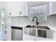 Stainless steel farmhouse sink and dishwasher complement white shaker cabinets at 110 Alta Vista Way, Davenport, FL 33837