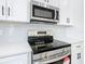 Stainless steel stove with microwave, white cabinets, and subway tile at 110 Alta Vista Way, Davenport, FL 33837
