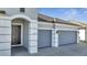 Home exterior showcasing a three-car garage, an arched entryway, and a brick paver driveway at 1130 Pando Loop, Orlando, FL 32824