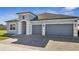 Home exterior featuring a three-car garage, an arched entryway, and a brick paver driveway at 1130 Pando Loop, Orlando, FL 32824