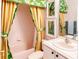 Charming bathroom with a tub, a white sink vanity, and patterned curtains at 153 Ventana Dr, Poinciana, FL 34759