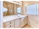 Bright bathroom featuring a large mirror, vanity with storage, and a window at 153 Ventana Dr, Poinciana, FL 34759