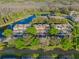 An aerial view showcases condos with a large pond, lush trees, and ample parking at 1717 Retreat Cir, Clermont, FL 34714