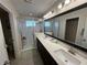 Bathroom featuring a double sink vanity, a walk-in shower with glass doors, and neutral tile flooring at 199 Macaulays Cv, Haines City, FL 33844