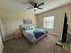 Cozy bedroom with a ceiling fan, a comfortable bed with blue bedding, and natural light from the window at 199 Macaulays Cv, Haines City, FL 33844