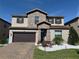 Charming two-story home with stone accents, a well-manicured lawn, and a dark brown garage door at 199 Macaulays Cv, Haines City, FL 33844