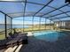 Inviting screened-in pool with brick pavers, chaise lounges, and a serene lake view at 199 Macaulays Cv, Haines City, FL 33844