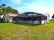 Backyard view featuring a screened-in enclosure attached to the house and lawn at 2235 Emperor Dr, Kissimmee, FL 34744