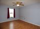A bright bedroom featuring hardwood floors, a ceiling fan, and a window with red curtains at 2235 Emperor Dr, Kissimmee, FL 34744