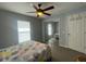 A well-lit bedroom featuring a ceiling fan, mirrored closet, and a cozy bed with patterned bedding at 24 Cordona Dr, Kissimmee, FL 34758