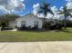 Charming home featuring a manicured lawn and mature palm trees against a bright blue sky with fluffy clouds at 24 Cordona Dr, Kissimmee, FL 34758