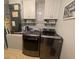 Modern laundry room with upper cabinets, shelving, and high-efficiency washer and dryer units at 24 Cordona Dr, Kissimmee, FL 34758