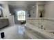 Luxurious main bathroom featuring a soaking tub, tiled floors, and a separate glass enclosed shower at 24 Cordona Dr, Kissimmee, FL 34758