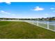 Lush green backyard featuring a white vinyl fence and a view of a peaceful lake at 2412 Country Pond Ct, St Cloud, FL 34771