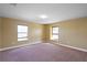 A bright, carpeted bedroom with neutral walls and natural light from two windows at 2412 Country Pond Ct, St Cloud, FL 34771