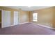 Bright bedroom with neutral paint, two white doors, a window, and soft carpet at 2412 Country Pond Ct, St Cloud, FL 34771
