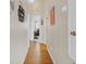 Inviting hallway with wood-look flooring, decorative wall art, and a view of an office space at 3686 Ricky Ln, St Cloud, FL 34772