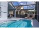 Lounge chairs sit next to in-ground pool within a screened enclosure with an outdoor seating area at 4614 Falcon Ave, Kissimmee, FL 34746