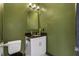 This bathroom features a modern vanity with granite countertops and stylish lighting fixtures on green walls at 486 Lake Shore Pkwy, Davenport, FL 33896