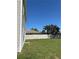 View of the green backyard with a wooden fence and the side of the house on a sunny day at 49 Inconnu Dr, Poinciana, FL 34759