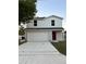 Two-story home with a two-car garage and a red front door, under a blue sky at 49 Inconnu Dr, Poinciana, FL 34759