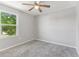 Neutral bedroom featuring plush carpeting, a ceiling fan, and a window showcasing exterior views at 49 Inconnu Dr, Poinciana, FL 34759