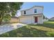 Inviting two-story home featuring a red front door, attached garage, and a well-maintained lawn at 49 Inconnu Dr, Poinciana, FL 34759