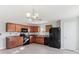A kitchen with dark wood cabinets, laminate countertops, black appliances, gray walls and laminate floors at 49 Inconnu Dr, Poinciana, FL 34759