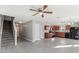 Spacious living room featuring modern flooring, wood cabinets in kitchen, and staircase to the second floor at 49 Inconnu Dr, Poinciana, FL 34759