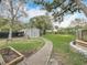 Large backyard showcases a well-maintained lawn, storage shed, and a winding sidewalk at 521 Florida Ave, St Cloud, FL 34769