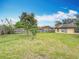 Spacious backyard with a wooden fence, green grass, and trees under a partly cloudy sky at 707 Divot Ln, Poinciana, FL 34759