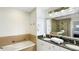 Well-lit bathroom with a soaking tub, granite countertop, double sinks and large framed mirror at 7602 Cabana Ct # 101, Reunion, FL 34747