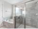 Bright bathroom featuring a shower with glass enclosure and a soaking tub tiled with stone look at 7649 Wilmington Loop, Kissimmee, FL 34747