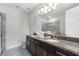 Bathroom with double sink vanity and walk-in shower featuring granite countertops at 7649 Wilmington Loop, Kissimmee, FL 34747