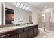 Elegant bathroom featuring a double vanity, granite countertop, and a glass-enclosed shower for a spa-like experience at 7649 Wilmington Loop, Kissimmee, FL 34747