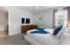 Sunlit bedroom with plush carpet, dresser with TV, and a king-size bed with blue accents at 7649 Wilmington Loop, Kissimmee, FL 34747