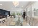 A modern dining room with an elegant glass table, decorative light fixture, and open access to the living room at 7649 Wilmington Loop, Kissimmee, FL 34747