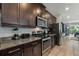 Open kitchen featuring granite countertops, dark cabinets, tile floors and stainless steel appliances in modern style at 7649 Wilmington Loop, Kissimmee, FL 34747