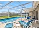 Screened-in pool area with a lounge chairs, table and chairs for poolside relaxation at 7706 Water Oak Ct, Kissimmee, FL 34747