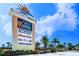 The sign for Sunset Walk displays a list of attractions and eateries under a sunny, blue sky at 8029 Sandy Toes Way, Kissimmee, FL 34747