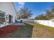 A well-maintained backyard featuring a concrete patio, mulch area, grassy lawn, and a white privacy fence at 919 Lake Charles Dr, Davenport, FL 33837
