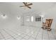 Bright living room with white tiled floors, ceiling fan, and a rocking chair near the window at 1102 Whitewood Dr, Deltona, FL 32725