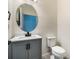Stylish half bathroom with gray vanity, stone countertop, and oval mirror at 1143 Seedorf Dr, Winter Haven, FL 33881