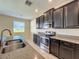 Modern kitchen features stainless steel appliances, granite counters, and dark wood cabinets at 15129 Driftwood Bend St, Winter Garden, FL 34787