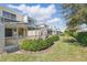 Exterior view of the property's back patio with a screened in enclosure, landscaping, and green grass at 1645 Retreat Cir, Clermont, FL 34714