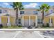 Inviting two-story townhome with a yellow exterior, well-kept landscaping, and prominent palm trees at 1645 Retreat Cir, Clermont, FL 34714