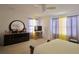 This bright bedroom has a dresser with mirror and light streaming through the curtained windows at 1737 Kato Way, Kissimmee, FL 34744