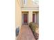 A quaint, covered front entryway featuring a red door, brick walkway, and colorful landscaping at 1737 Kato Way, Kissimmee, FL 34744