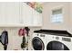 Well-organized laundry room with sleek washer and dryer, storage cabinets, and convenient hooks at 17418 Blazing Star Cir, Clermont, FL 34714