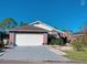 Charming single-story home featuring a two-car garage, lush landscaping, and brick accents at 181 Whisper Wood Ct, Kissimmee, FL 34743